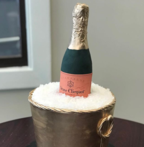 A wedding cake in the shape of a bottle of champagne in a bucket of ice